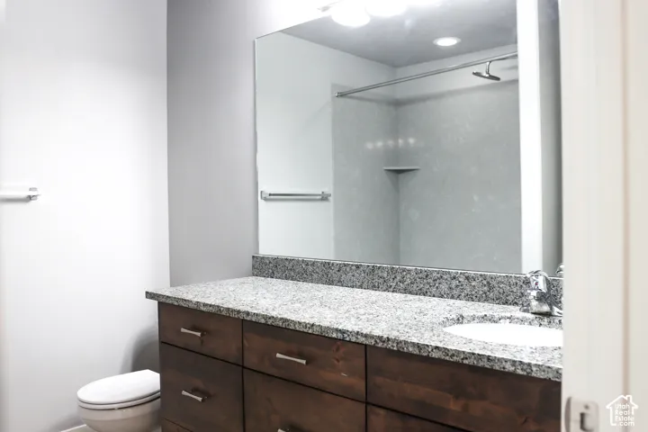 Bathroom featuring a dark wood-finish vanity with chrome hardware, a light-toned stone countertop, and an integrated white sink
