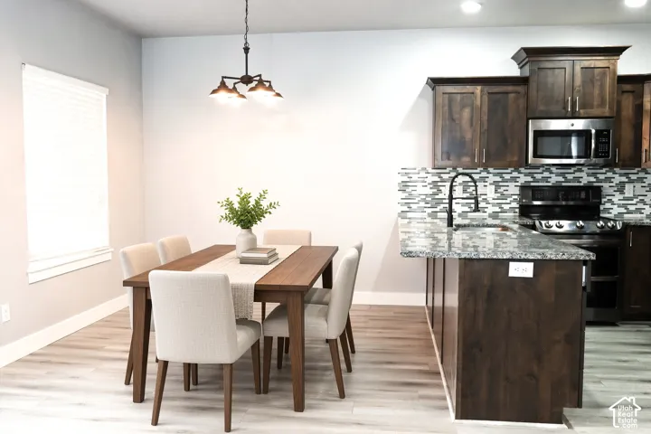 Light wood-finish flooring with a multi-light chandelier and a window with blinds