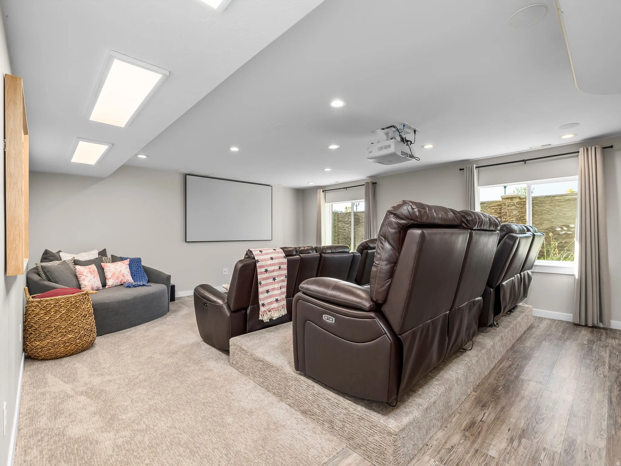 Dedicated media room featuring a large projector screen, ceiling-mounted projector, and tiered seating platform