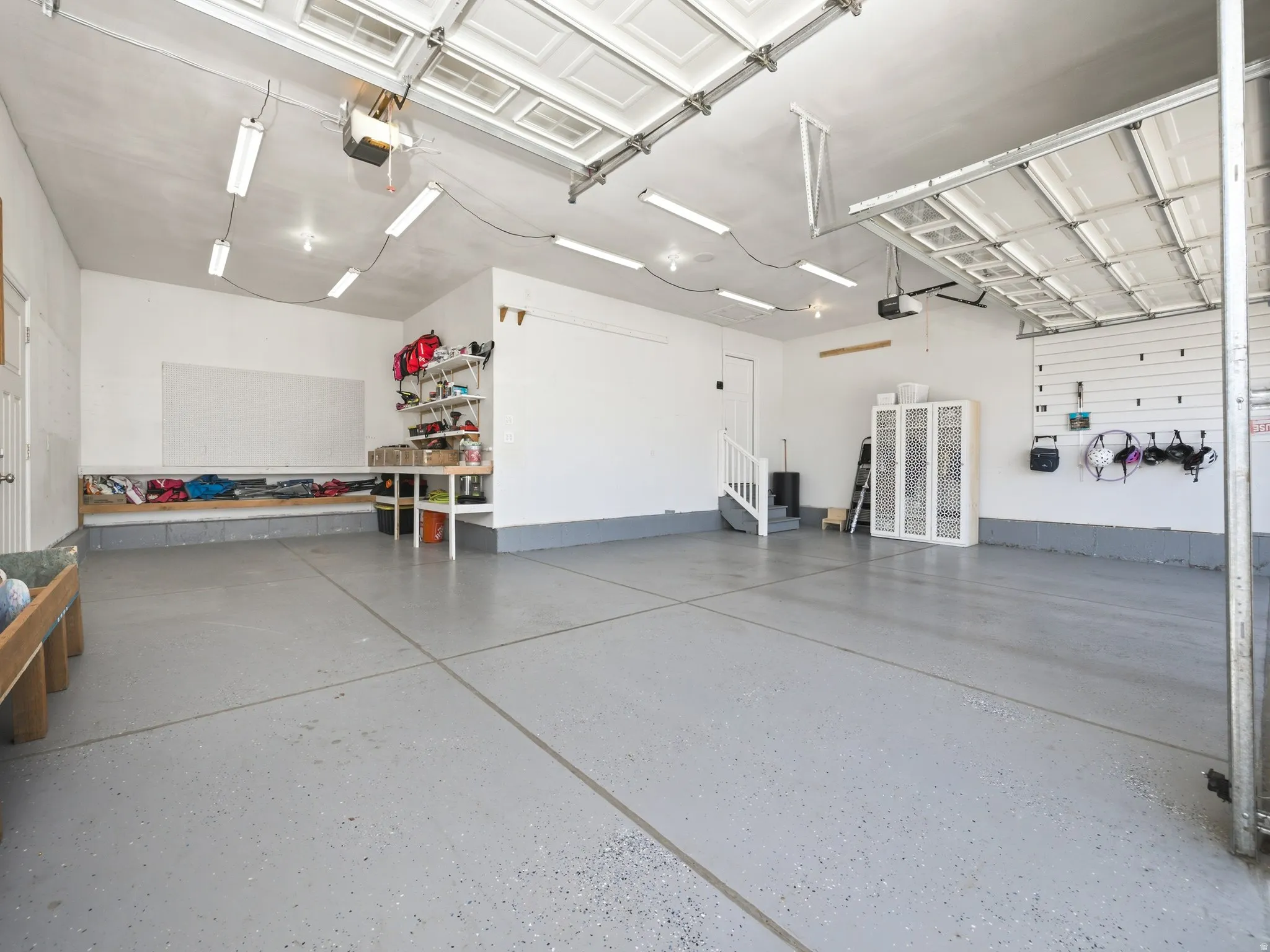 Spacious garage featuring a durable epoxy-coated floor, bright overhead fluorescent lighting, and a white interior paint scheme