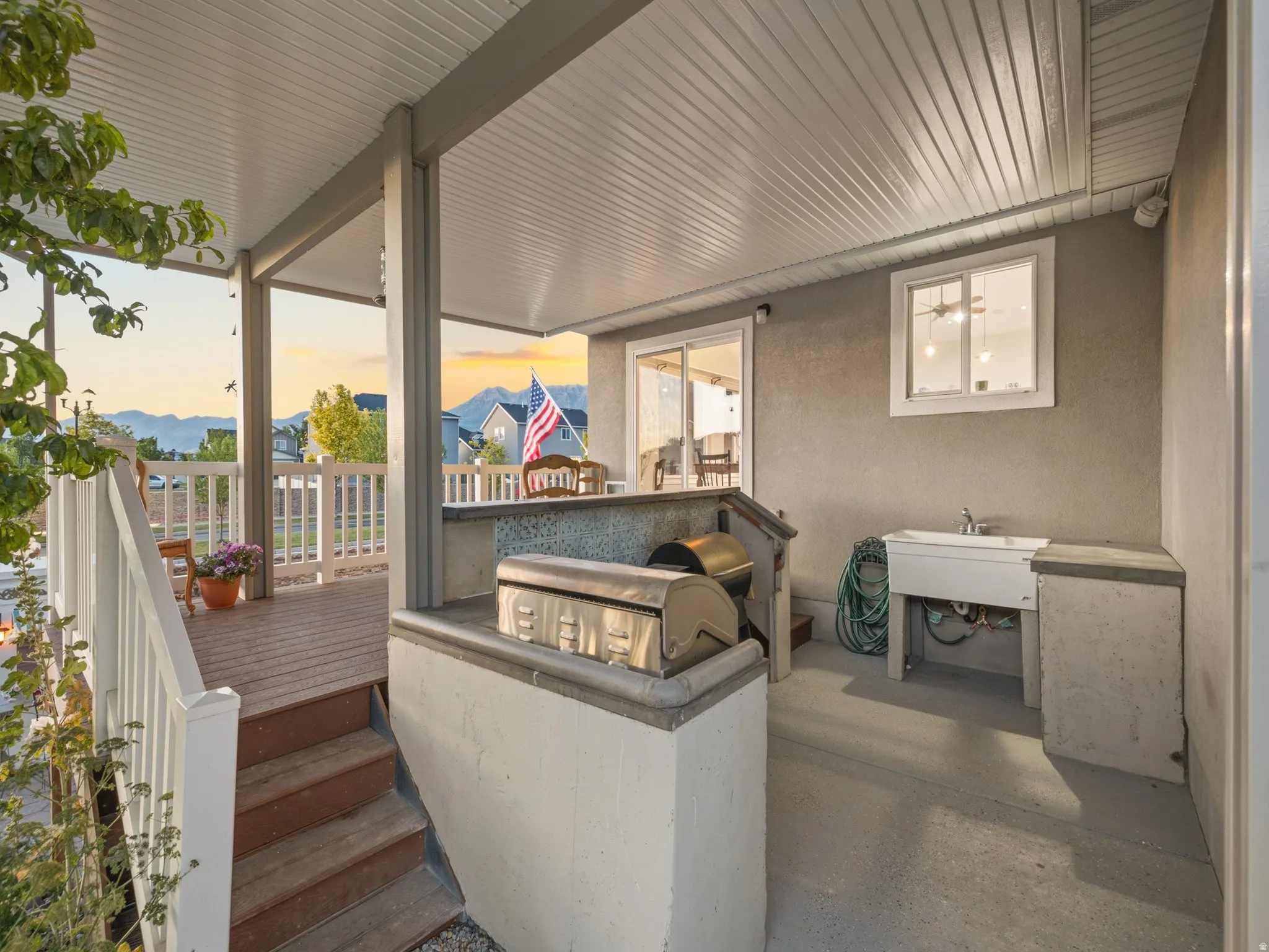 Covered outdoor patio with concrete flooring, built-in utility sink, and a grill station