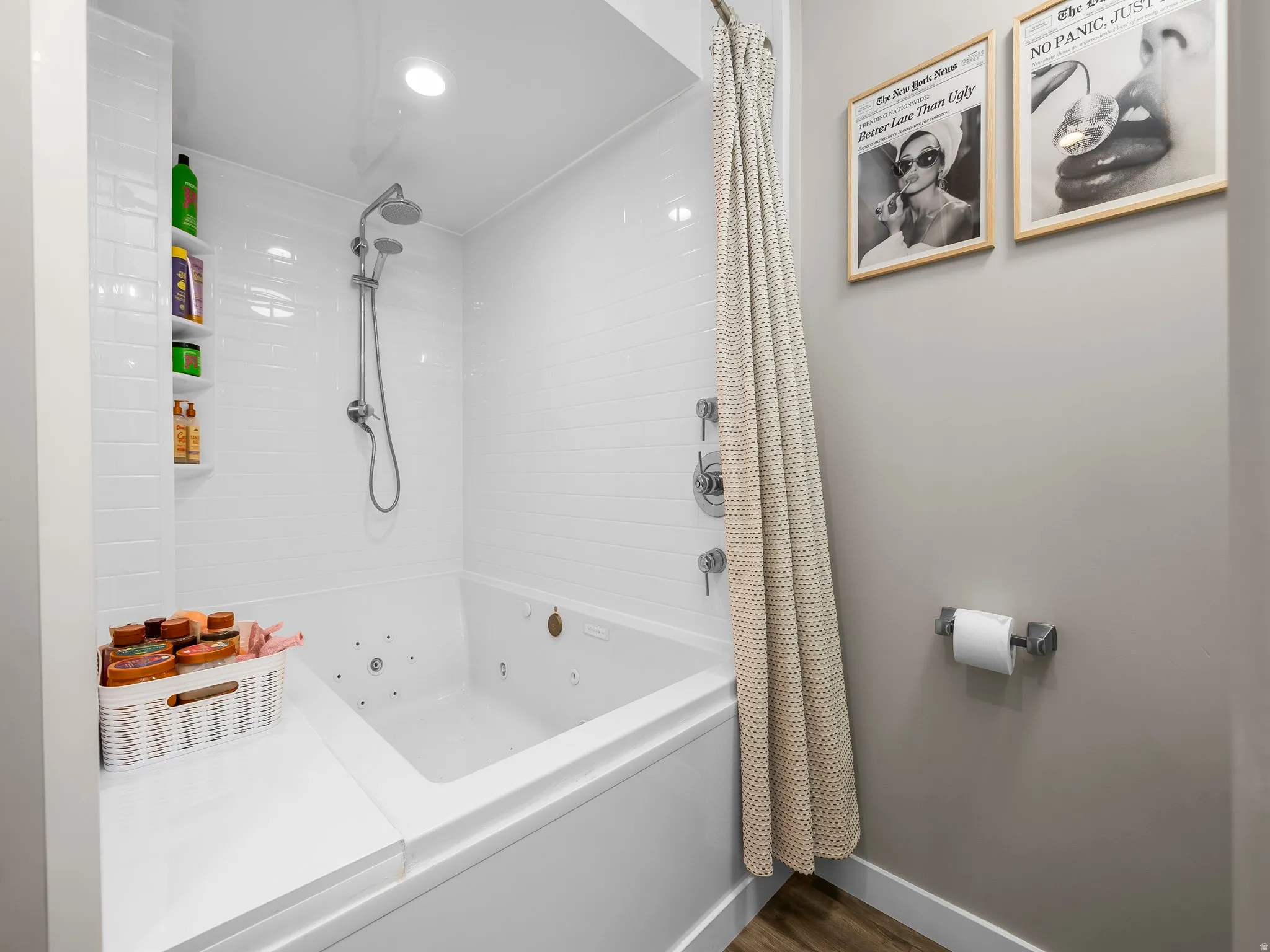 White subway tile shower surround with integrated shelving and a built-in jetted tub featuring a rain showerhead and handheld sprayer