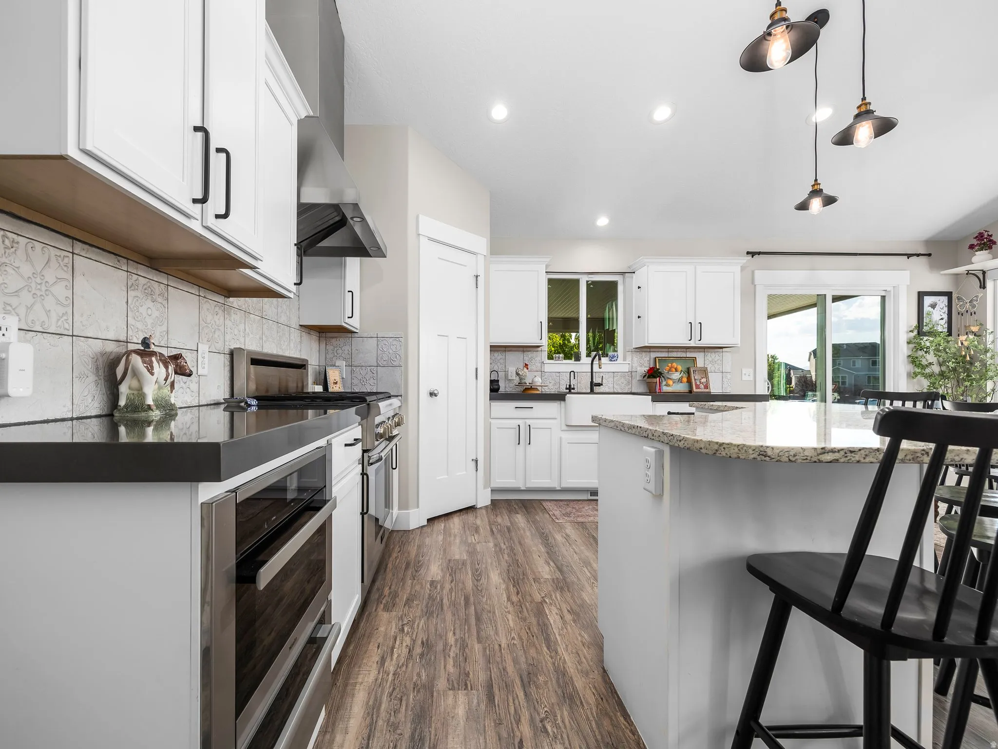 Bright kitchen featuring white cabinetry with dark hardware, a center island with a light-toned countertop, and wood-finish flooring