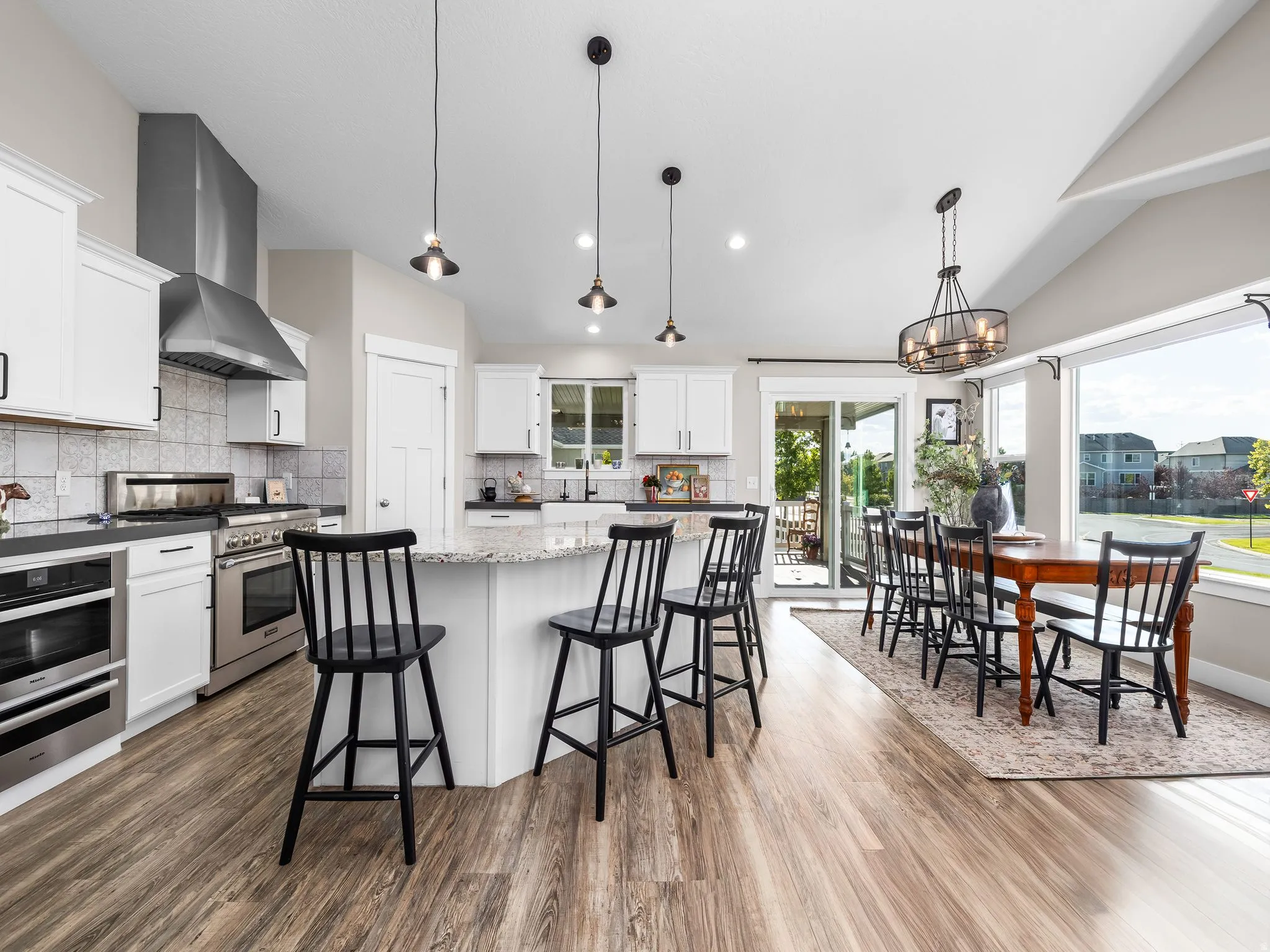 Open-concept kitchen and dining area featuring wood-finish flooring, white cabinetry, and stainless steel appliances