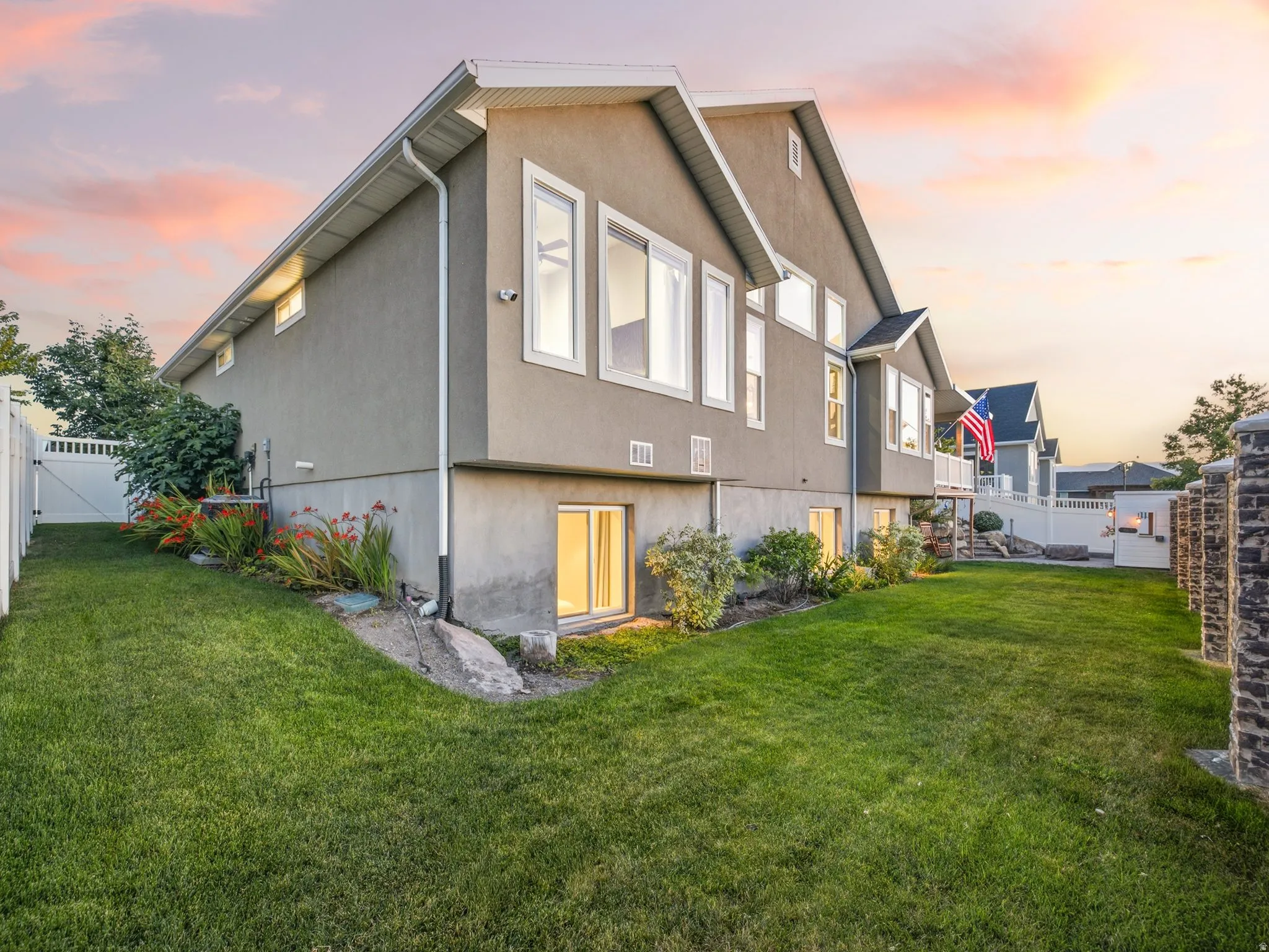 Exterior stucco siding with multiple windows and a white vinyl fence