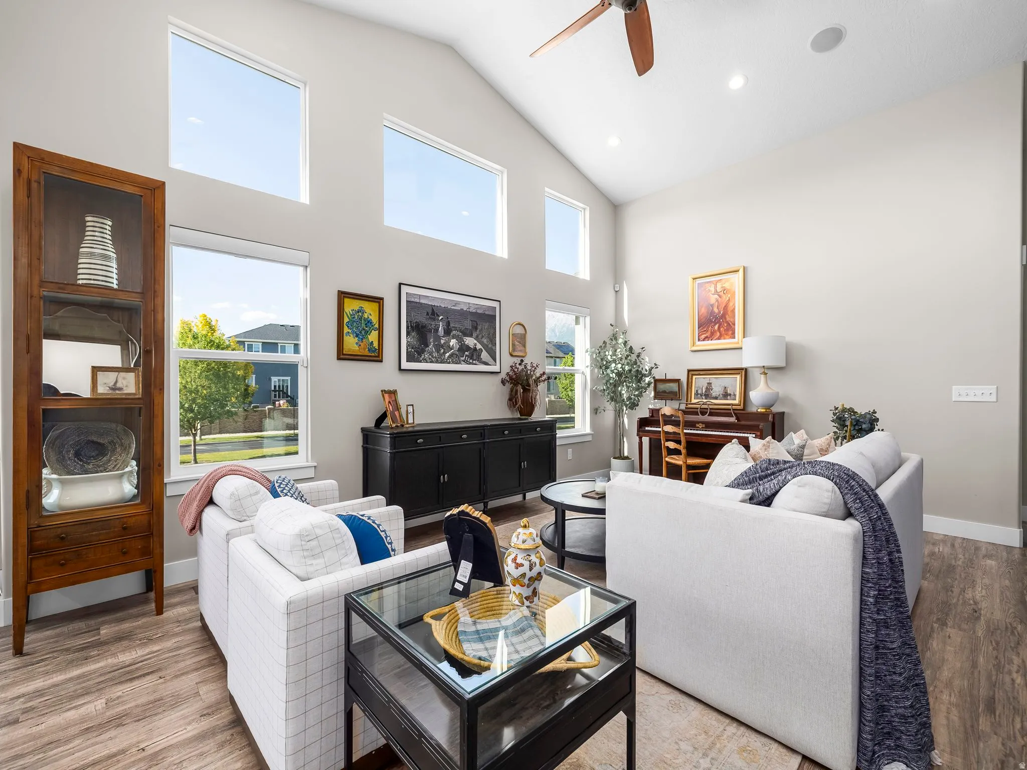 Vaulted ceiling living area featuring wood-finish flooring, recessed lighting, and multiple large windows