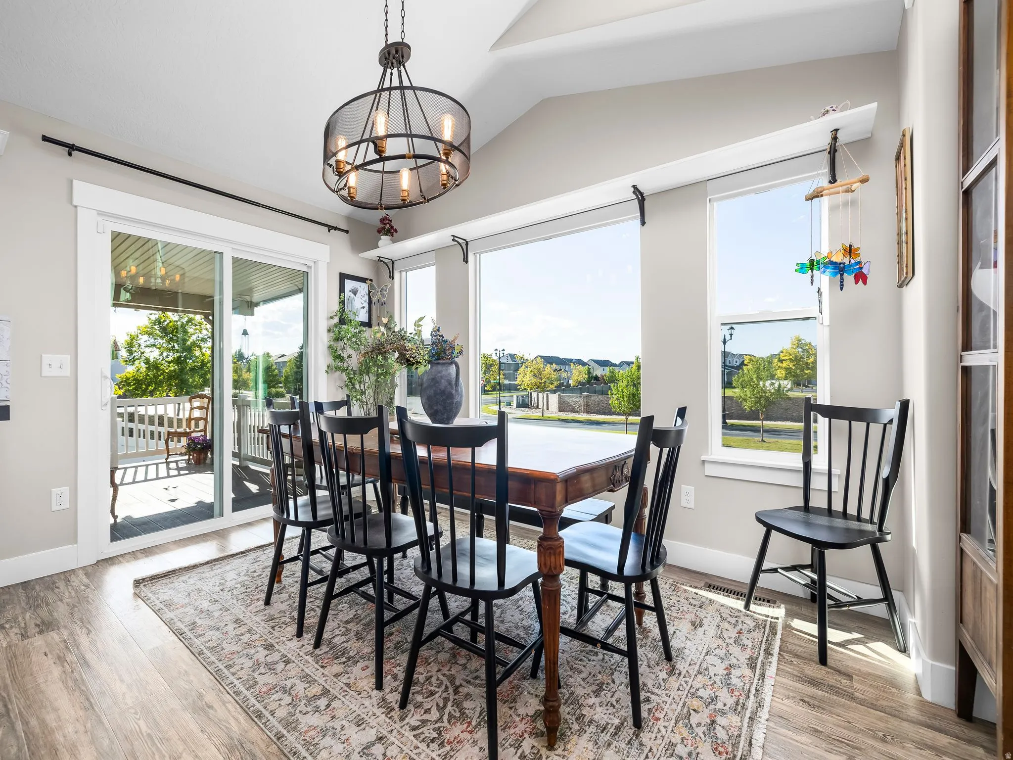 Dining area featuring wood-finish flooring, vaulted ceilings, and a contemporary chandelier