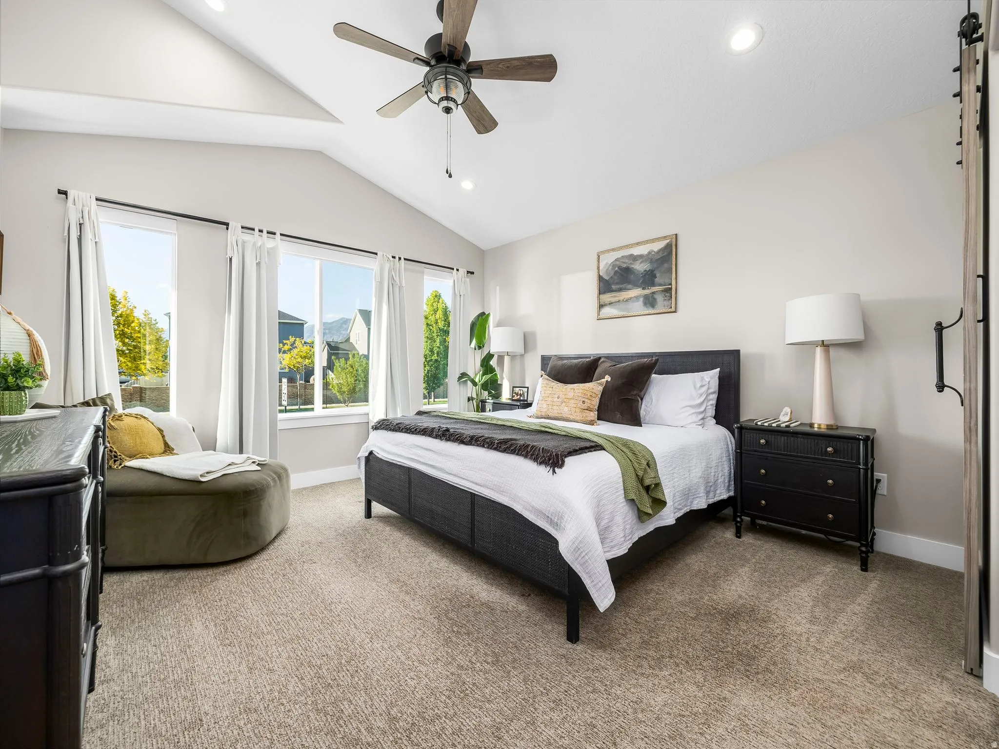 Spacious room featuring vaulted ceilings, recessed lighting, a ceiling fan, broad windows, and plush carpeting