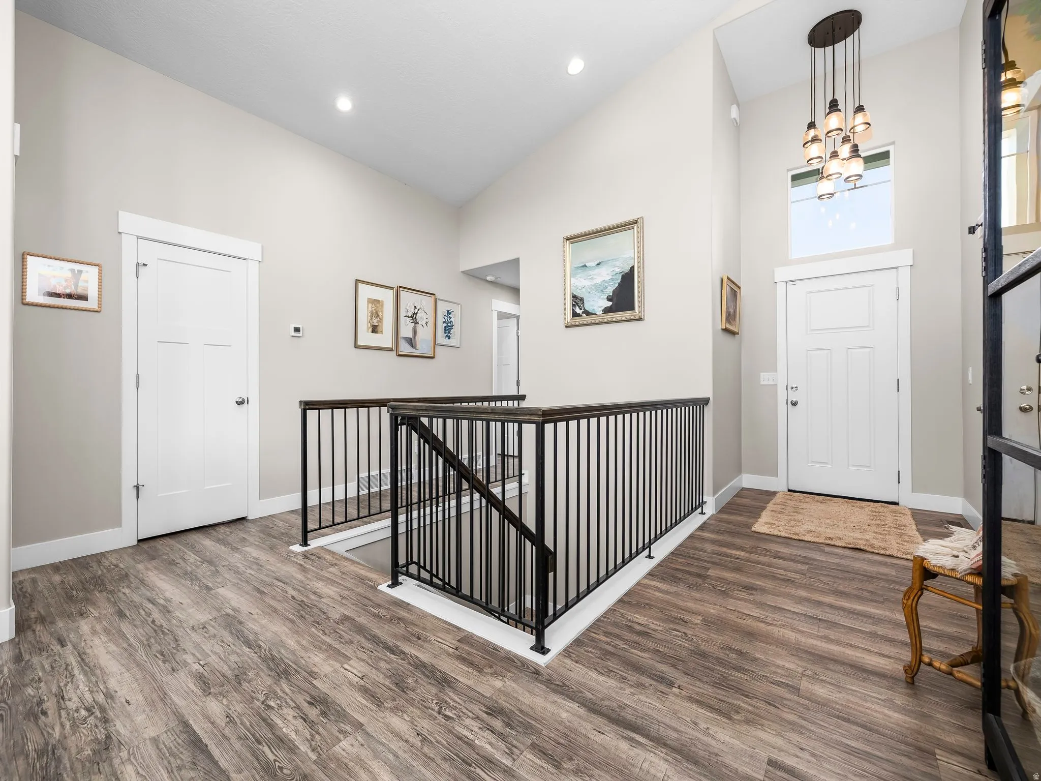 Entryway featuring wood-finish flooring, a contemporary chandelier, and a two-story vaulted ceiling