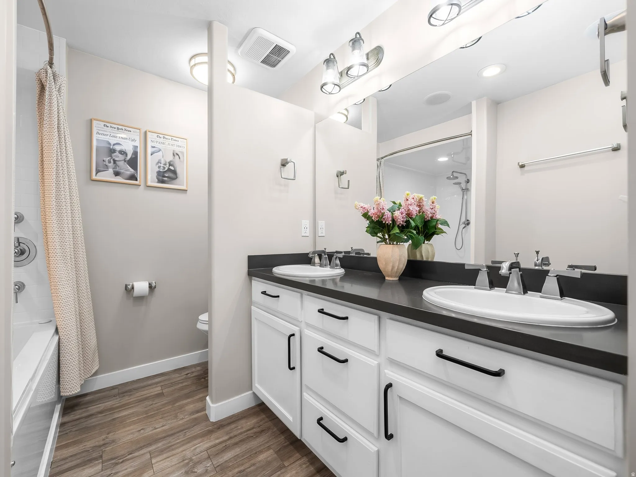 Double vanity featuring white cabinetry with black hardware, undermount sinks, and a dark countertop