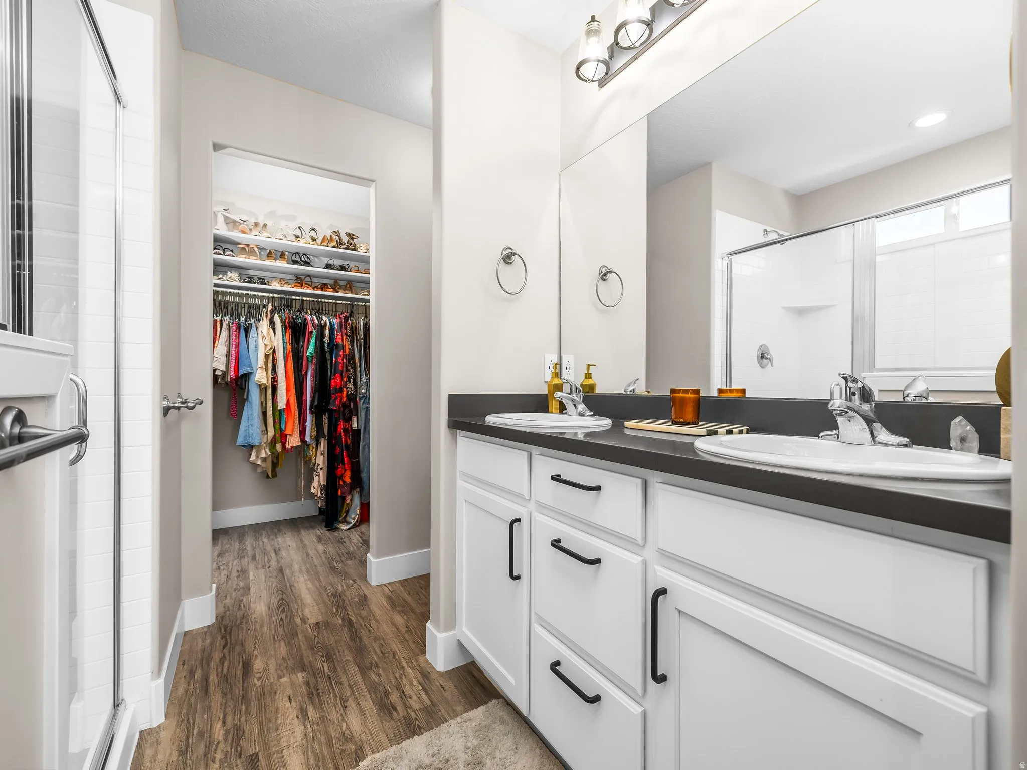 Double vanity with undermount sinks, dark countertop, and white cabinetry featuring matte black hardware
