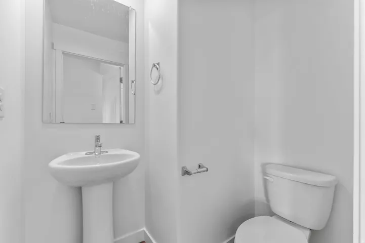 Pedestal sink with chrome faucet, complemented by a rectangular frameless mirror
