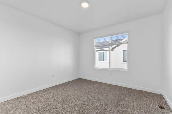 Room featuring neutral-toned carpeting, crisp white walls, and a recessed ceiling light fixture