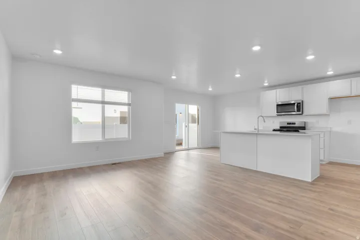 Open-concept living space featuring wood-finish flooring, recessed lighting, and a neutral color palette