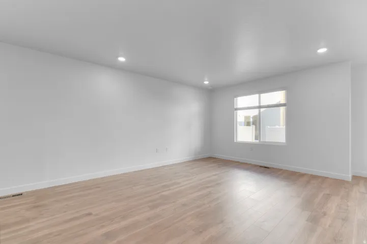 Spacious room featuring wood-finish flooring, recessed lighting, and a large multi-pane window