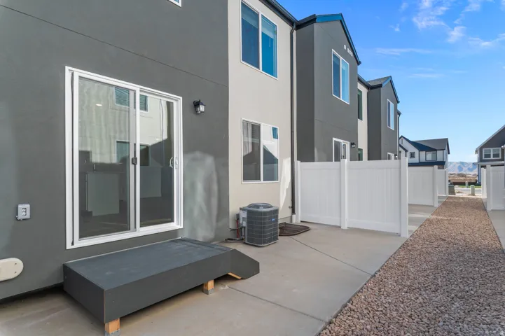Patio area featuring concrete surfacing, a gravel path, and white privacy fencing