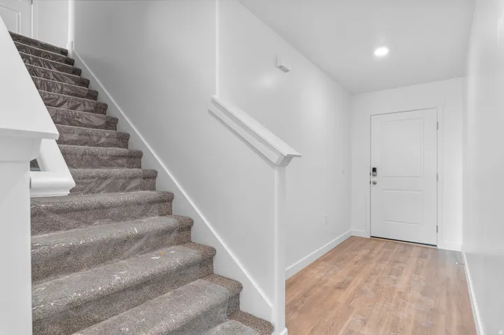 White interior entry featuring a wood-finish flooring and a white paneled door with contemporary hardware