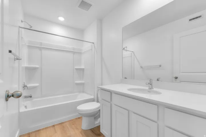 Bathroom featuring a white vanity with an integrated sink, polished chrome faucet, and a large wall-mounted mirror