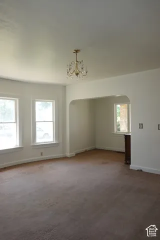 Spacious room featuring a brass chandelier, multiple windows with white trim, and a curved wall section