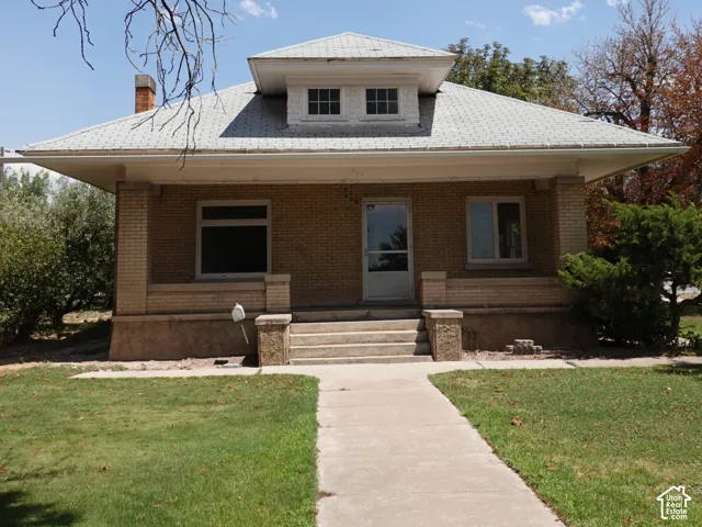 Craftsman-style home featuring a brick exterior, covered front porch, and dormer window