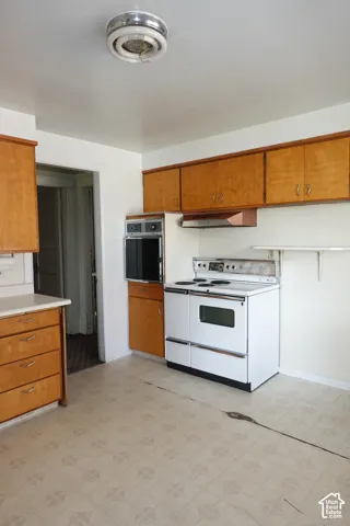 Kitchen featuring wood cabinetry, white countertops, a built-in oven, and a freestanding range
