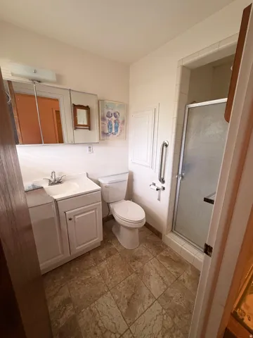 Bathroom featuring a glass-enclosed shower, white vanity with integrated sink, and patterned tile flooring
