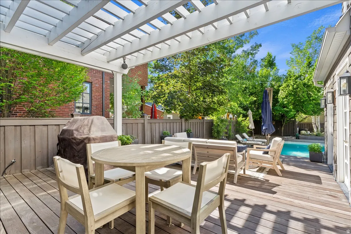 Expansive outdoor deck featuring a white pergola, wood-finish decking, and privacy fencing
