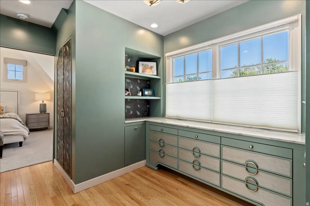 Custom built-in cabinetry with decorative hardware, integrated shelving, a solid surface countertop, and wood-finish flooring