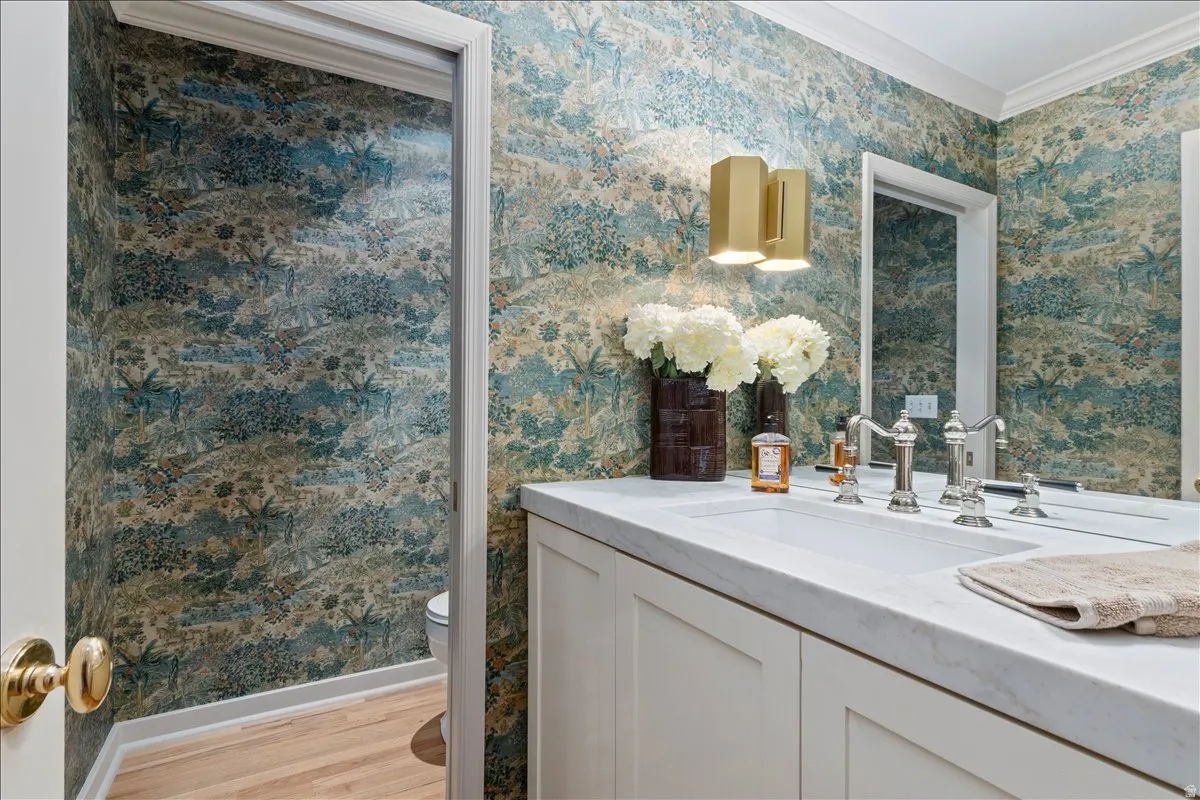 Powder room featuring botanical print wallpaper and crown molding