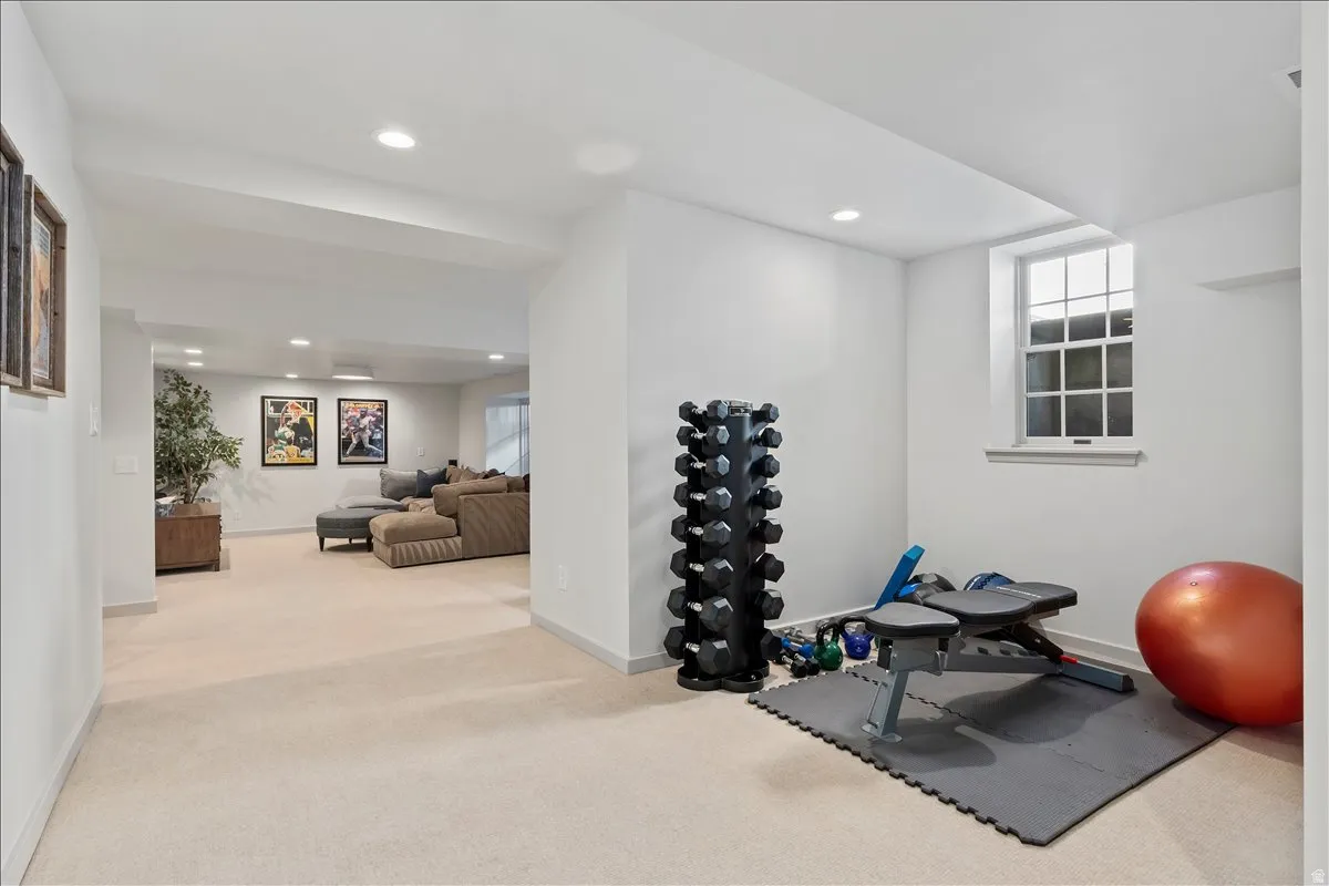 Versatile lower level featuring a dedicated fitness area with window, recessed lighting, and neutral carpeting throughout