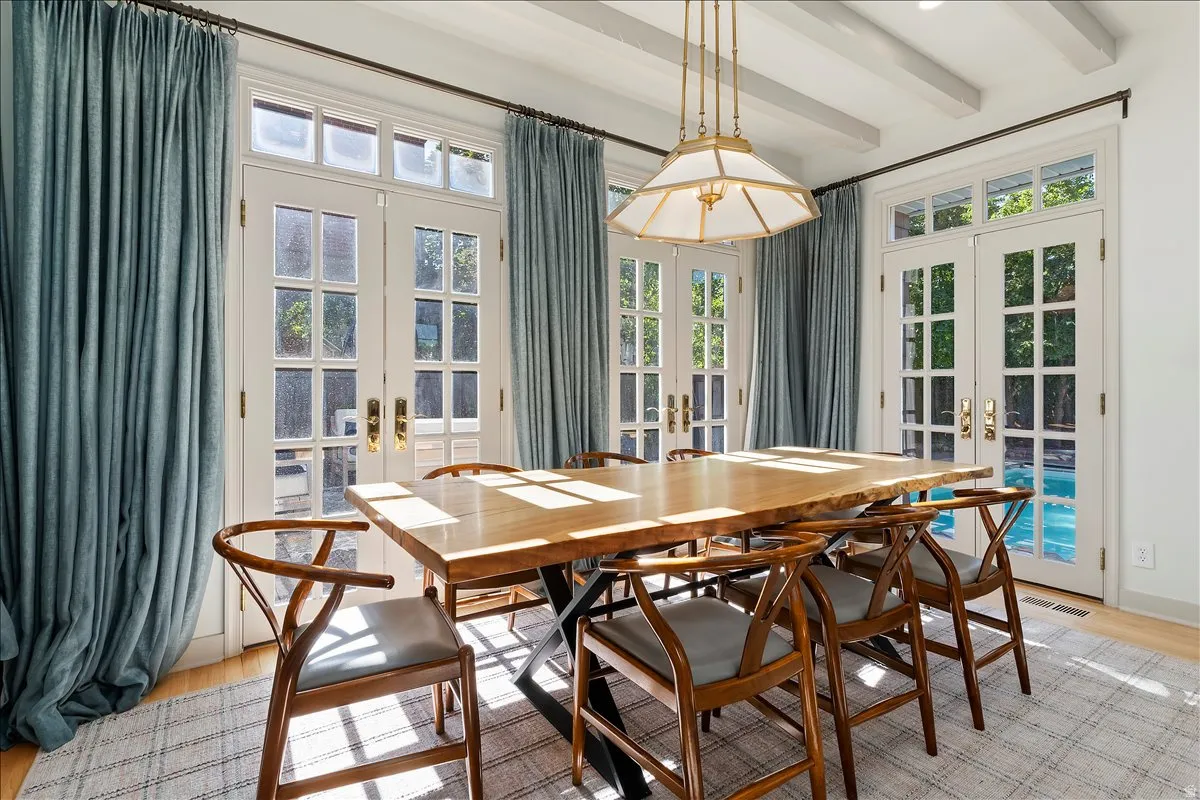 Dining area featuring a wood-finish table, multiple French doors, hardwood flooring, and a coffered ceiling
