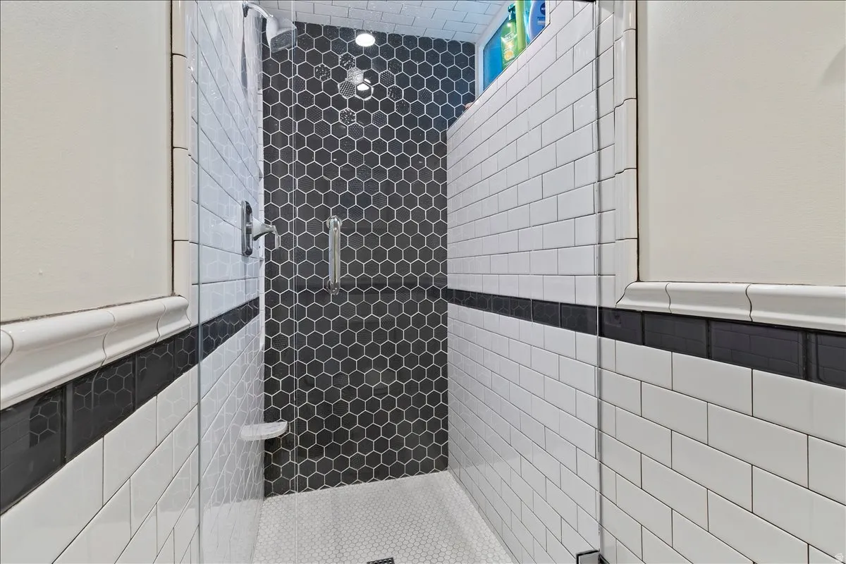 Walk-in shower featuring clear glass enclosure, hexagon tile accent wall, subway tile walls, and a recessed light fixture