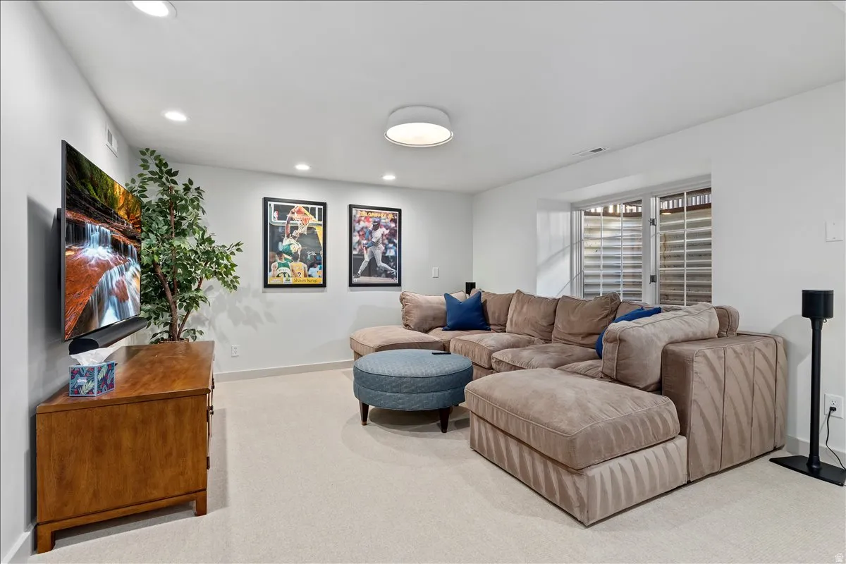 Carpeted living area featuring recessed lighting, a ceiling-mounted light fixture, white walls, and a window with horizontal blinds