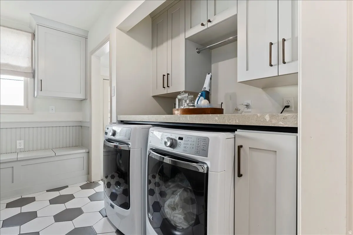 Laundry area featuring a built-in bench, hexagonal floor tiling, and upper and lower cabinetry