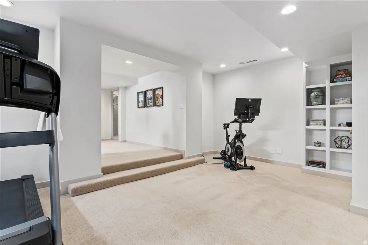 Carpeted lower level featuring recessed lighting, built-in shelving, white baseboards, and painted walls