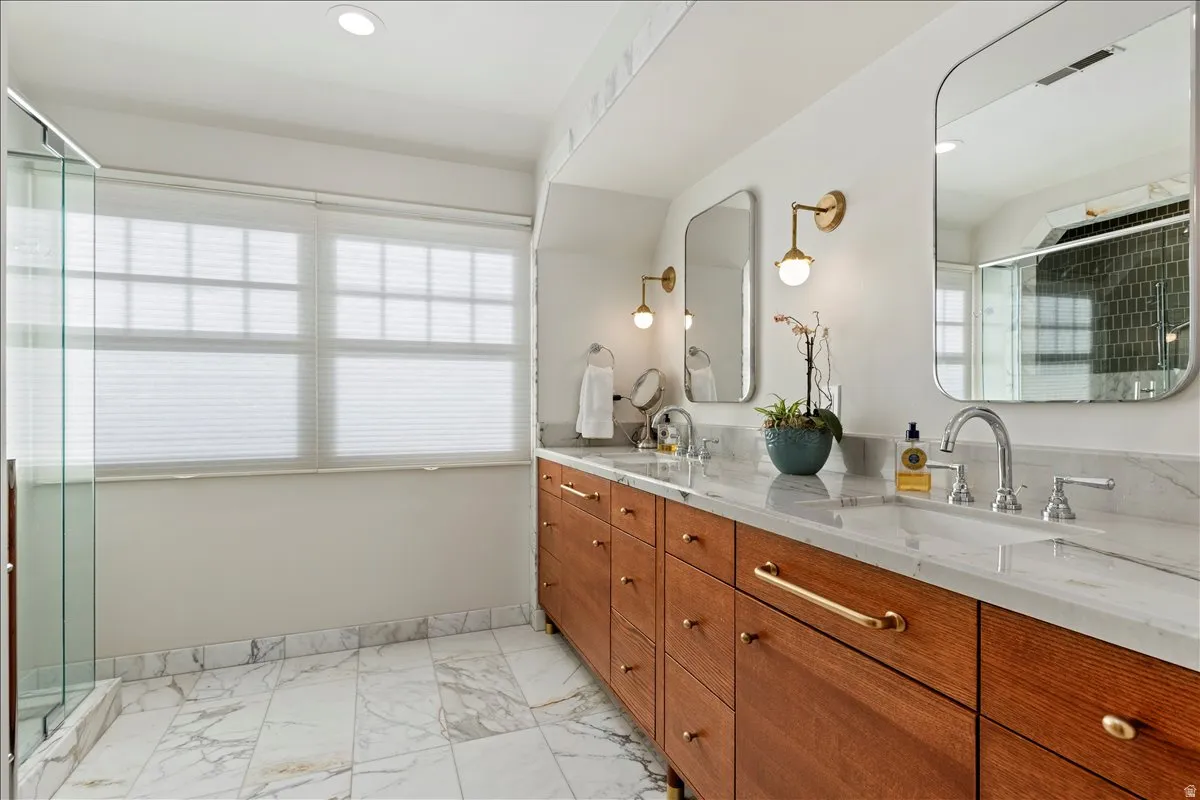 Dual vanity with wood-finish cabinetry, stone-finish countertops, and chrome fixtures