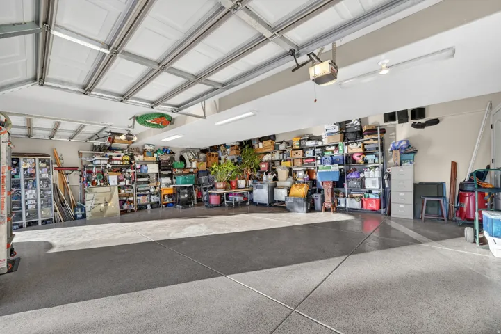 Spacious garage featuring a durable epoxy floor, overhead fluorescent lighting, and multiple garage doors
