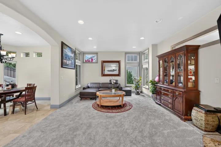 Spacious living area featuring light gray carpeting, recessed lighting, and multiple windows