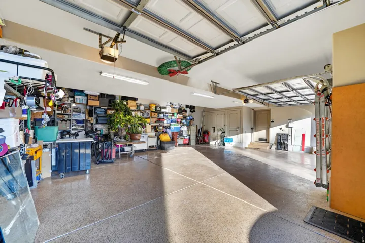 Spacious garage with epoxy-coated concrete flooring, dual overhead garage doors, and built-in shelving
