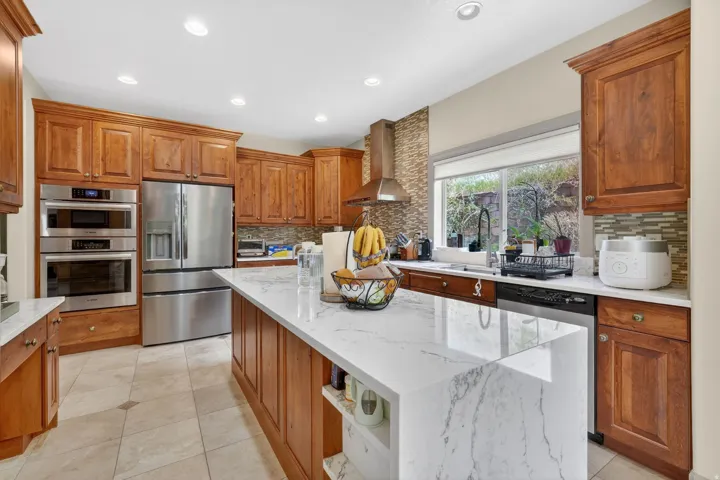 Kitchen featuring light wood cabinetry, stainless steel appliances, a center island with a white countertop, recessed lighting, and a window above the sink