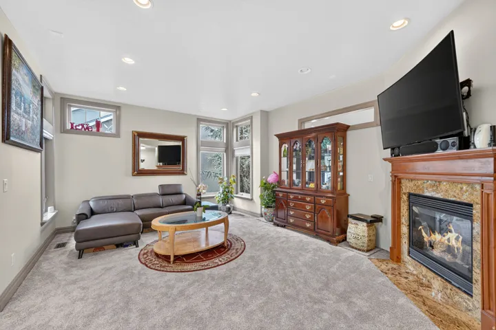 Living area featuring wall-to-wall carpeting and a fireplace with a light-toned stone surround and a wood mantel