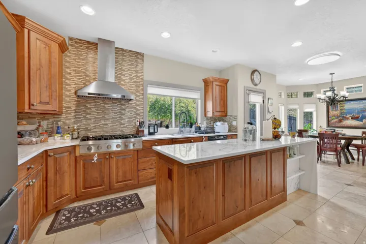 Kitchen featuring wood cabinetry, stone countertops, a stainless steel range hood, a gas range, and recessed lighting