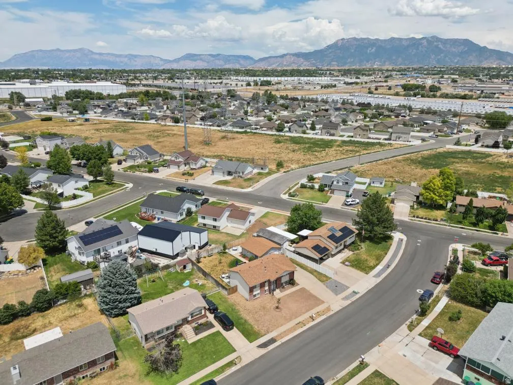Residential neighborhood featuring a variety of single-family homes, mature trees, and mountainous terrain in the background