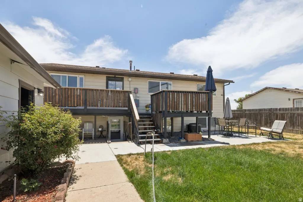 Rear exterior featuring a multi-level wood deck, ground-level patio, and a manicured lawn