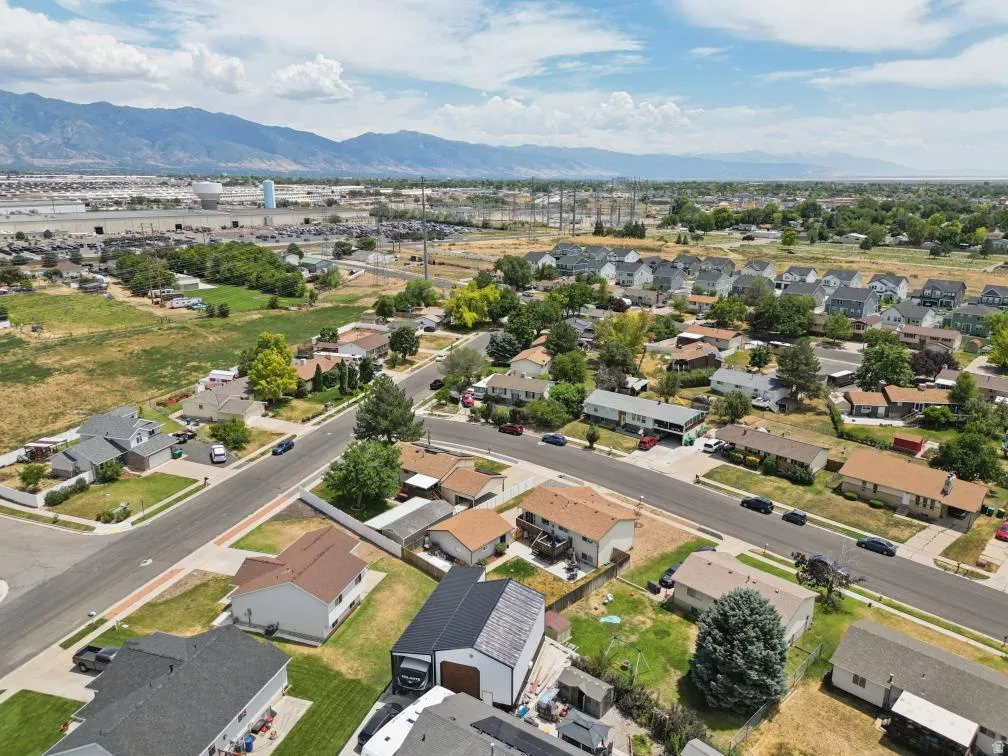 Aerial perspective of a residential street with single-family homes, mature trees, and mountainous scenery in the distance