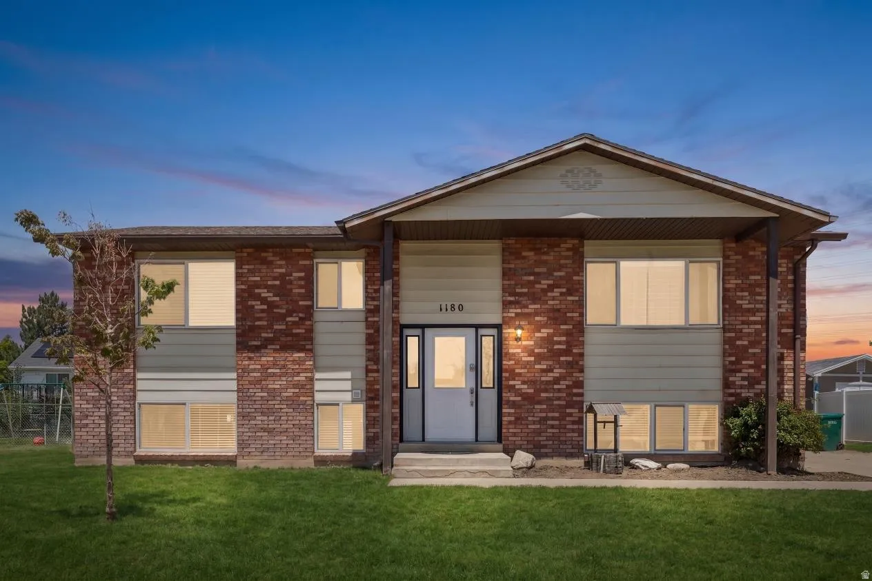 Two-story residential exterior featuring brick and horizontal siding accents, a prominent front entry with sidelights, a covered porch, and a manicured lawn (Digitally enhanced to show lawn potential)