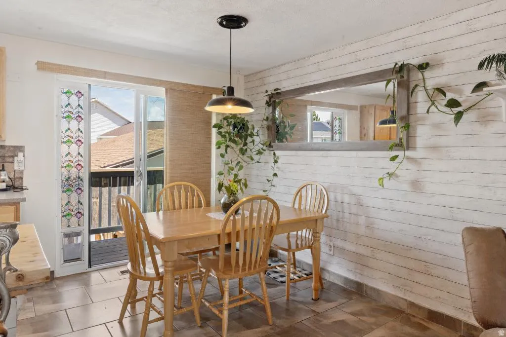 Dining area featuring a wood-finish dining table and chairs, tile flooring, and a shiplap accent wall