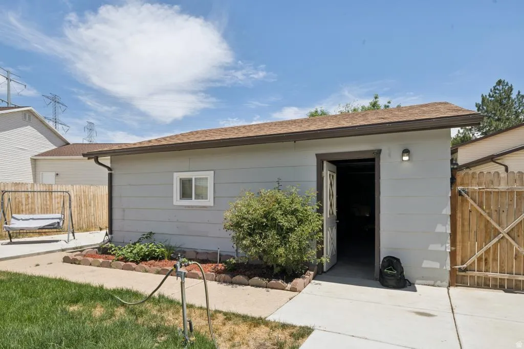 Detached accessory structure with light gray siding, a brown shingle roof, and a single white window