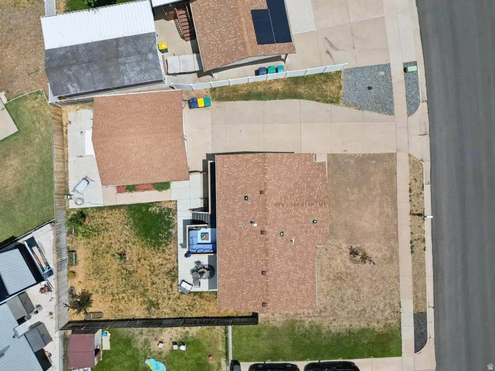 Aerial view showcasing a property with a shingle roof and a paved driveway