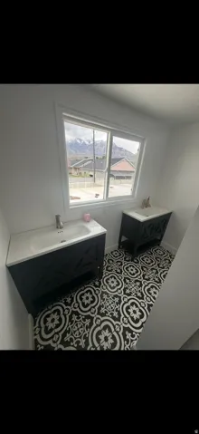 Dual black vanities with integrated sinks, set against a backdrop of patterned floor tiling and a window framing distant mountains